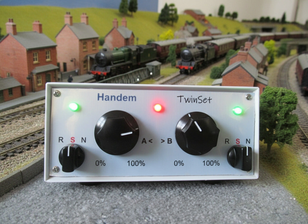 Model train controller with knobs and lights labeled 'Handem' and 'TwinSet' on a railway layout background.